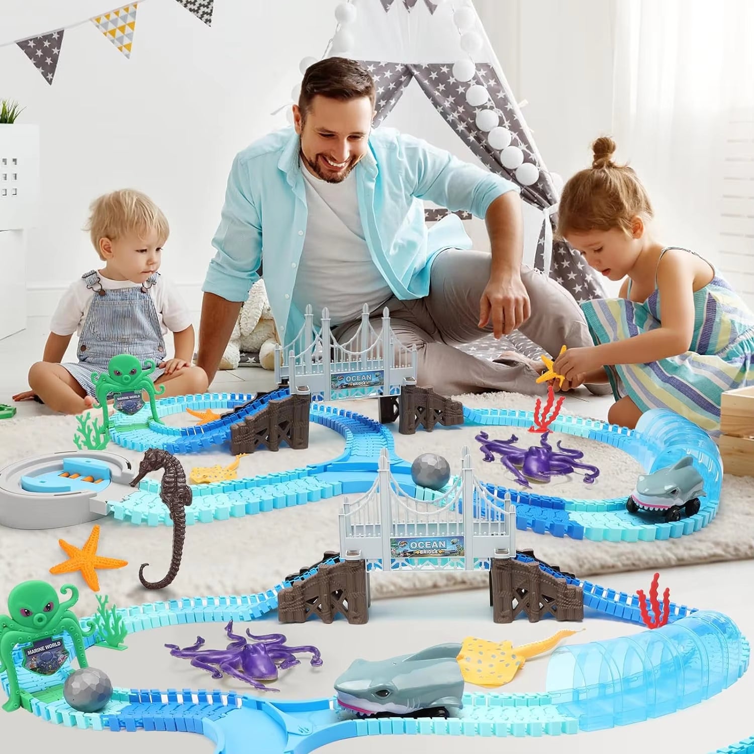 Kids and parent playing with a large ocean adventure track set featuring blue tracks, sea creature figures, bridges, and marine‑themed educational toy pieces on a carpeted floor.