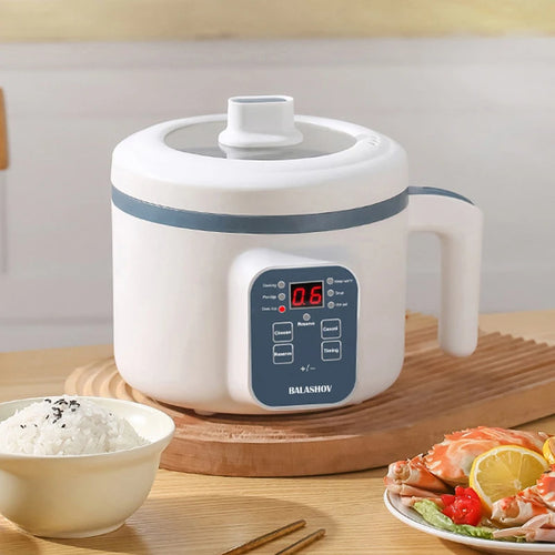 Compact electric rice cooker with digital display, ceramic non-stick pot, and cooked rice beside it.
