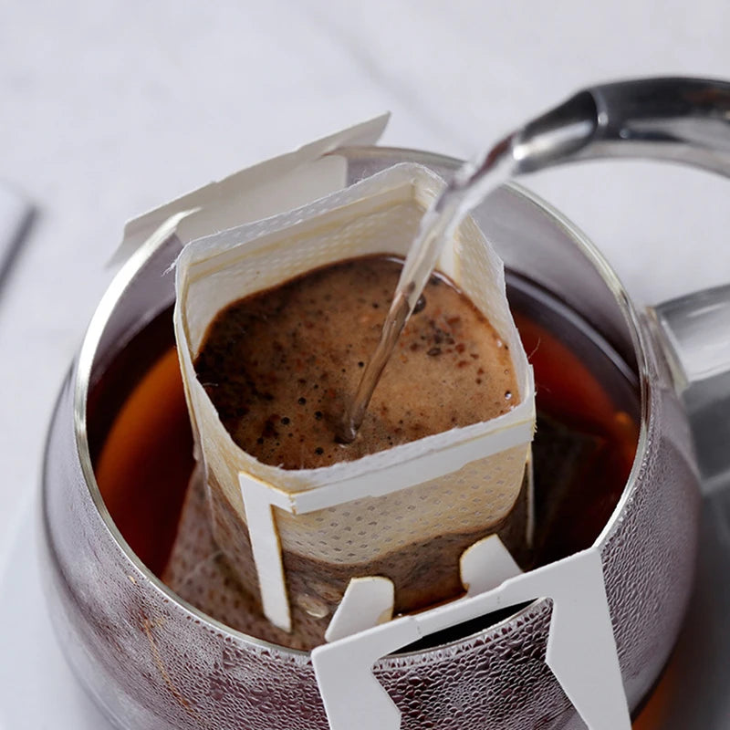 Hanging ear coffee filter bag in use over a cup with ground coffee